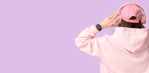 Stylish woman with smartwatch and headphones on lilac background, back view. Banner for design