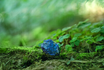 Blue mineral Chalcopyrite (Copper Pyrite) close up on natural blurred forest background. Gemstone...
