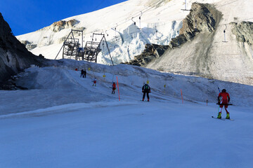 Skiers pulled by ski lift towards mountain Allalinhorn ski slope and snow mountain panorama during...