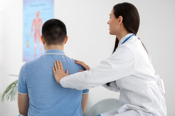 Obraz premium Female doctor checking posture of young man in clinic