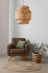 Cozy brown armchair with cushion and houseplant near white wall