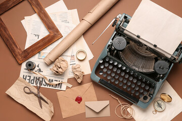 Composition with vintage typewriter, envelope, paper and scissors on brown background