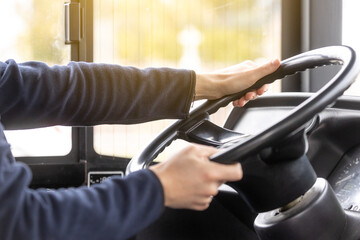 Close up of bus driver hands on the steering wheel during driving the bus, public transport concept