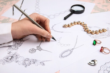 Female jeweler drawing adornment on grunge table, closeup