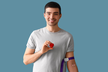 Young blood donor with applied medical patch and heart on blue background