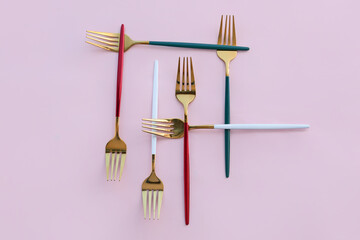 Golden forks on pink background