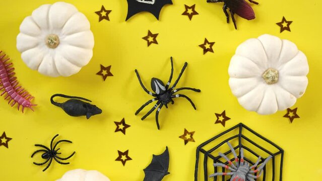 Halloween background with black bats, spiders, pumpkin and stars. Modern Holiday design. Halloween party border spinning on yellow. Flat lay, top view, copy space. Thanksgiving fall trendy decoration.