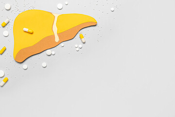 Yellow paper liver with pills on grey background