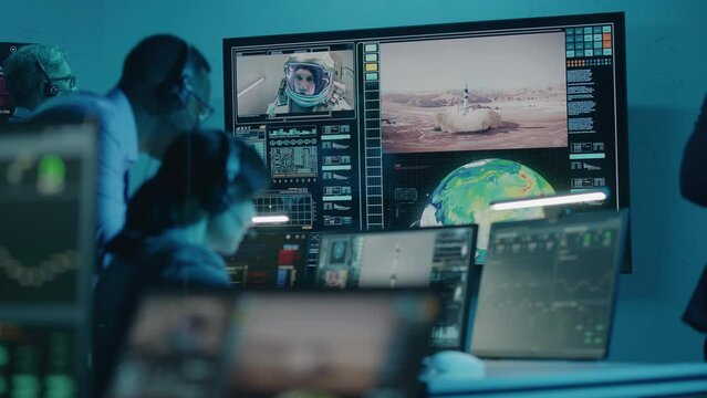 Flight control operators monitor space mission on computers in command center, have communication with astronaut. Team watch successful space rocket launch on big digital screen. Space exploration.