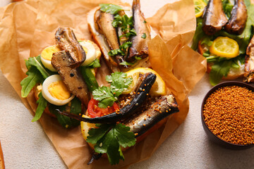 Tasty sandwiches with canned smoked sprats on white background