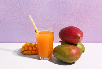 Glass of fresh mango smoothie on purple background