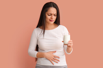 Displeased young woman with lactose intolerance on beige background