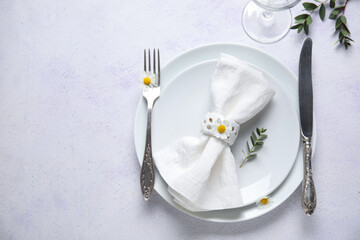 Plates with folded napkin, silver cutlery and glass on grunge white background