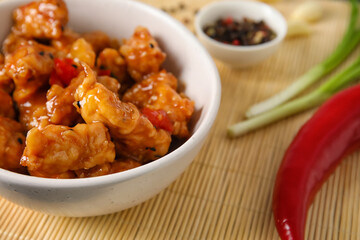 Bowl with tasty sweet and sour chicken on table, closeup