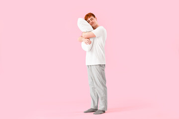 Young man with soft pillow on pink background