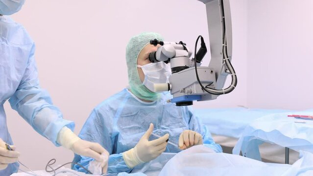 Surgeon performing eye surgery with microscope in operating room