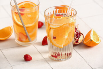 Glasses of infused water with orange slices on white tile table
