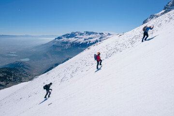 Naklejka na ściany i meble mountaineers climbing harmoniously on the steep and sloping summit