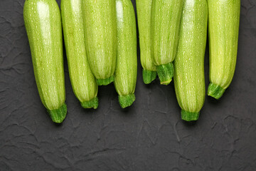 Many fresh green zucchini on black background