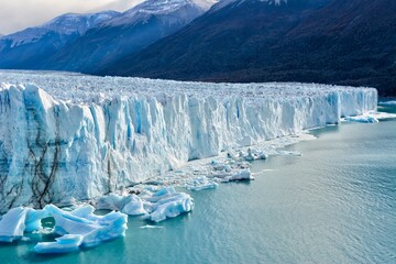Photo of a magnificent glacier wall towering over a pristine body of water in Argentina's Perito Moreno - obrazy, fototapety, plakaty