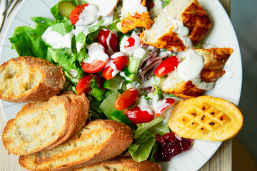 close up of a healthy delicious salad with tomatoes, cheese, chicken, vegetables and baguette. A light, healthy meal rich in protein. Caesar salad