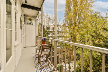 Fototapeta premium a balcony with chairs and table on the left hand side, looking out to the trees in the back yard