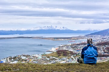 Photo of a person enjoying the panoramic view of the city from a hill in Ushuaia, Tierra del Fuego