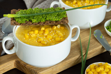 Corn soup with fresh garlic pate in white bowl. Healthy food on wooden background. Vegan cuisine