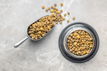 Dry kibble pet food. Dog or cat food in scoop on gray table. Top view.