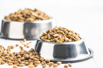 Dry kibble pet food. Dog or cat food in bowl on white table.