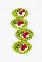 Spinach round waffles with cheese cream and raspberries. White background