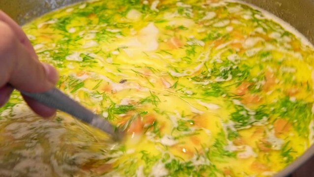 Cheddar cheese soup. Vegetables carrot, potatoes, herbs boiled in a thick broth. White Soup boiling in a saucepan. Preparing Bouillon. Cooking cream broth, making in a steel pot in a kitchen Close-up.