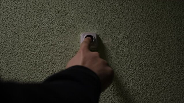 Close up of a male finger pressing a ring bell in the evening. Concept. Impatient man pressing button of a door bell.