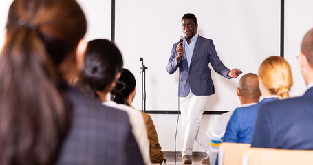 Expressive male lecturer speaking at corporate motivational coaching and training conference