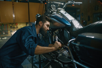 Man repairing motorcycle using wrench while working at repair workshop