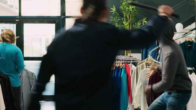 African american thief stole stylish clothes in clothing store, being caught by asian security guard. Robber running from bodyguard, trying to escape the crime accusations. Robbery concept