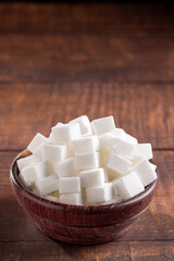 White sugar cubes in wooden bowl.