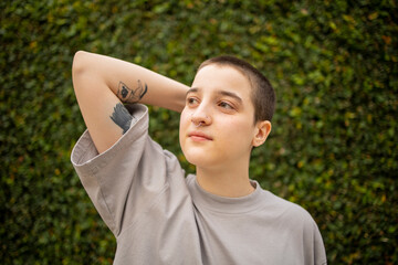 Portrait of Latin transgender generation z person with the short hair looking away.  - obrazy, fototapety, plakaty