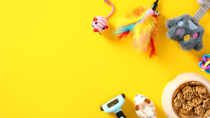 Banner layout for a pet supply store. Cat food in a bowl, cat toys, hair care brush on yellow background. Flat lay, top view.