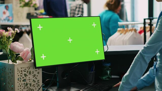 Shopping centre with chroma key greenscreen mock up computer screen, employee working in modern boutique. Manager looking at isolated display, standing at counter desk in clothing store