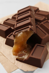 Tasty chocolate bars with caramel on white table, closeup