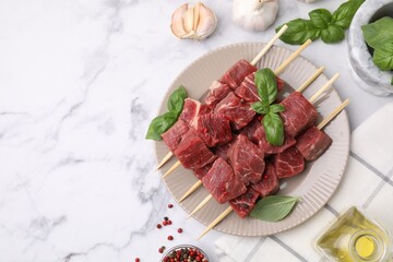 Flat lay composition with cut fresh beef meat on white marble table. Space for text