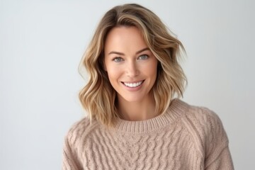 Fototapeta premium Close-up portrait of beautiful young woman with blond hair looking at camera and smiling while standing against white background