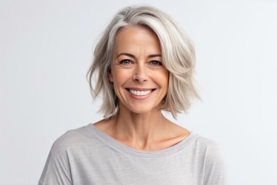 Portrait of happy mature woman with short grey hair looking at camera over white background