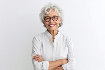 Portrait of a smiling senior woman wearing eyeglasses standing with arms crossed against white background