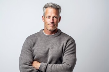 Handsome man with grey hair standing with arms crossed over white background