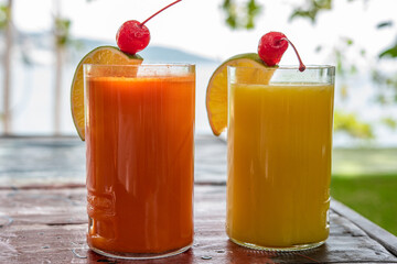 Dos vasos de jugo uno de zanahoria y otro de Naranja