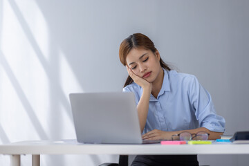 Portrait of tired young business Asian woman work with documents tax laptop computer in office. Sad, unhappy, Worried, Depression, or employee life stress concept