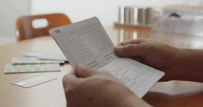 Hands opening bank book to check balance on wooden table
