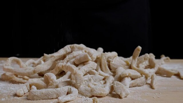 dropping pasta line with flour on a wooden board - macro shot zoming out